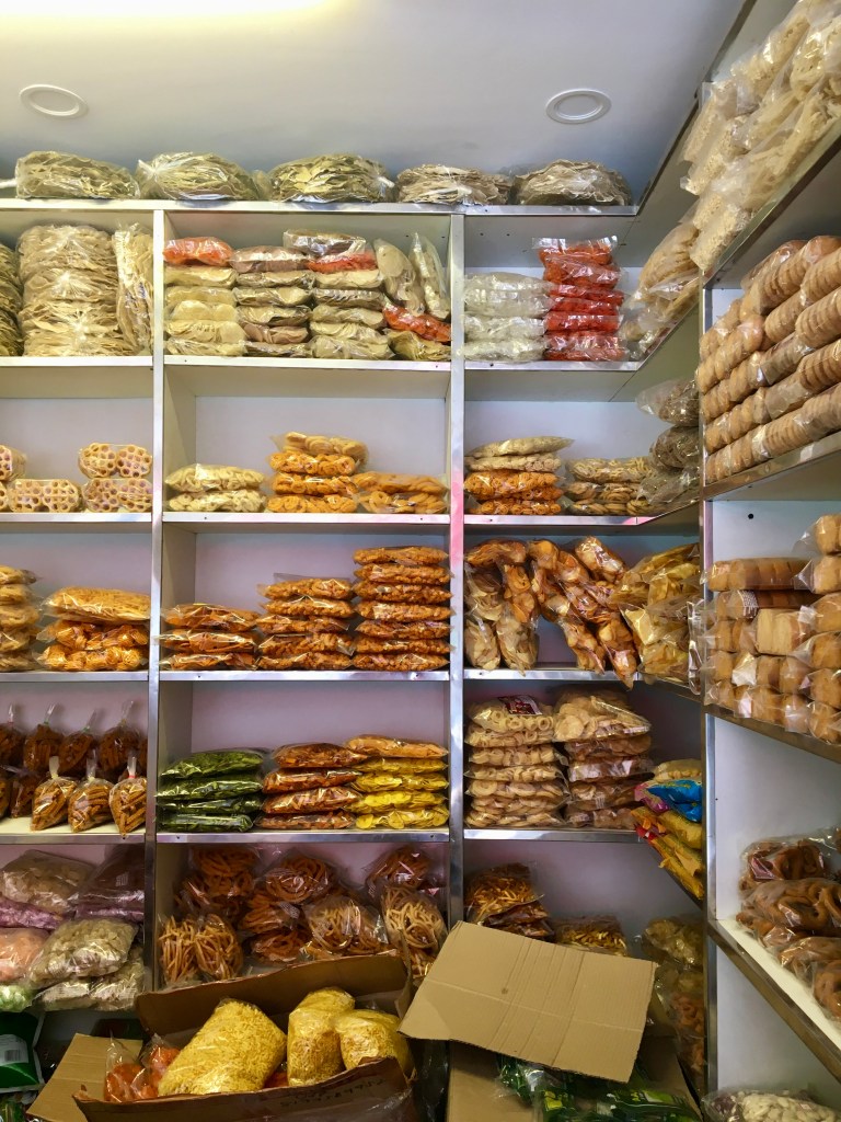 A shelf displaying a variety of packaged snacks and food items commonly found in Mangalore Stores, showcasing colorful packaging and different shapes of snacks.